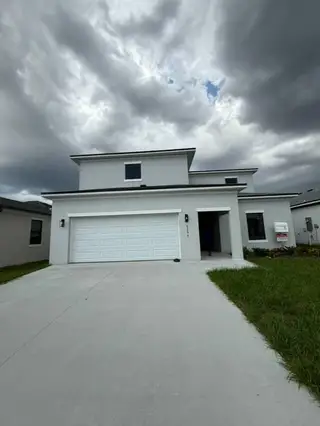 A modern white home with a sleek design and spacious driveway in On Villa Pass by Onx Homes (Mascotte, FL).