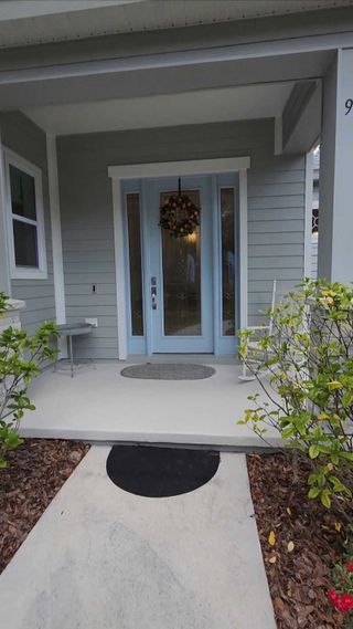 Street view A welcoming porch with soft blue door and elegant landscaping in Azalea Walk by Gallery Homes (Deland, FL).