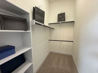 Spacious walk-in closet with ample hanging space and shelving for effortless organization in Veramendi by Coventry Homes (New Braunfels, TX).