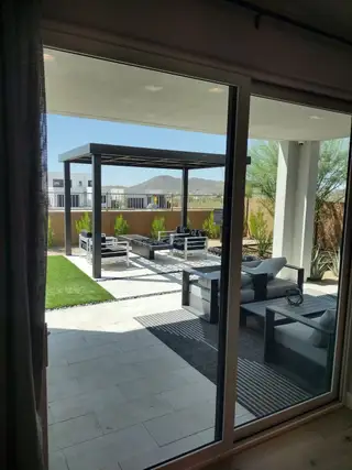 A modern patio with sleek outdoor furniture, a pergola, and a view of distant hills for serene relaxation.