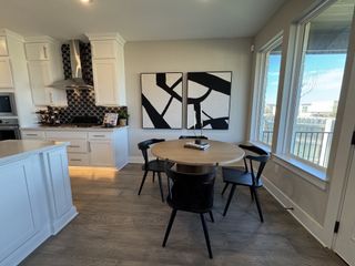 Modern kitchen with sleek white cabinets, bold backsplash, and a cozy dining nook with large windows.
