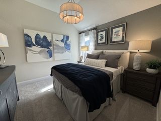 A cozy bedroom featuring elegant artwork, plush bedding, and soft lighting with a modern chandelier.
