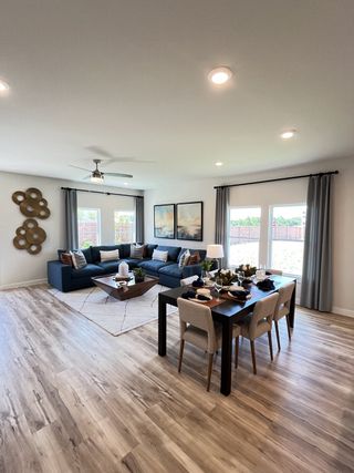 A modern living-dining area with wood flooring, a sleek dining set, and a cozy sectional under soft lighting.