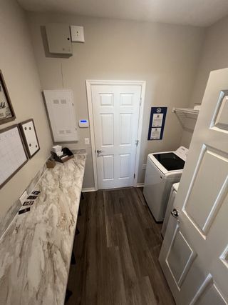 A functional laundry room with a marble-look countertop, sleek cabinetry, and modern appliances.