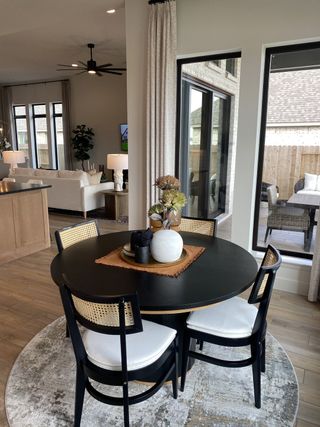 Model Home A cozy dining area with a sleek black table, modern chairs, and warm natural light illuminating the space.