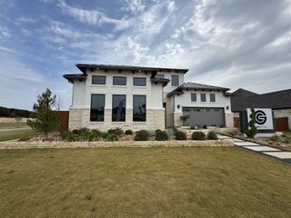 Street view A modern stone and stucco home with landscaped yard in Heights at San Gabriel by GFO Home (Georgetown, TX).