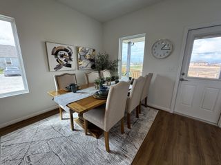 Model Home A cozy dining room with elegant artwork, a wooden table with seating for six, and a large wall clock.