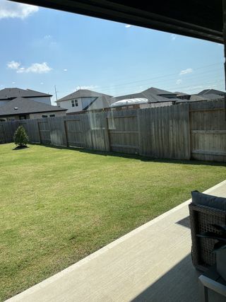 A serene backyard view showcasing a spacious lawn and a cozy patio seating area.