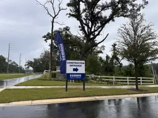 A rainy entrance to new homes in Wynwood by D.R. Horton, surrounded by lush greenery in Ocoee, FL.