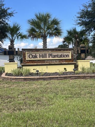 A welcoming entrance with palm trees invites you to Oak Hill Plantation by Adams Homes in Ocala, FL.