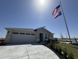 Street view A modern home with a spacious garage and neatly landscaped yard in Lakeside Meadows by Meritage Homes (Pflugerville, TX).