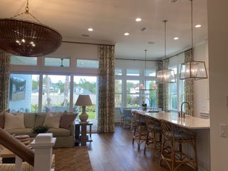 A cozy open-concept living area with a large island, wicker seating, and elegant lighting complements the bright, airy space.