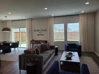 Model Home A modern living room with a cozy sofa, chic armchairs, and ample natural light, perfect for relaxation and entertaining.