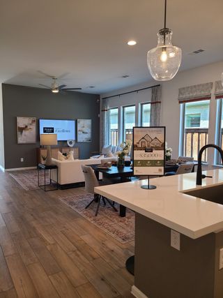 Model Home A modern open living room with a cozy seating area, elegant dining space, and wood flooring.