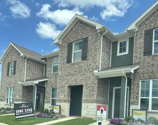 Street view A charming brick townhome with elegant shutters in Seven Oaks Townhomes by HistoryMaker Homes, located in Tomball, TX.
