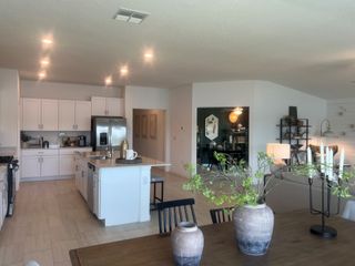 A contemporary open-plan kitchen and dining area with sleek white cabinets, ambient lighting, and stylish decor elements.