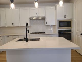 A modern kitchen with white cabinetry, sleek countertops, a central island, and stainless steel appliances.