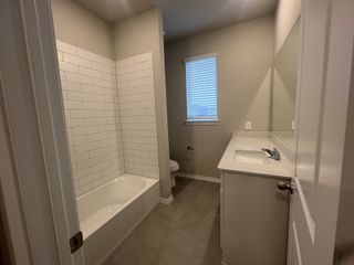 A modern bathroom featuring a sleek vanity, tiled flooring, and a classic white-tiled bathtub for a clean look.