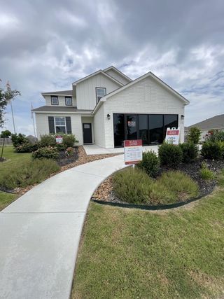 Street view A charming white brick home with a modern facade and landscaped lawn in Weston Oaks by View Homes (San Antonio, TX).