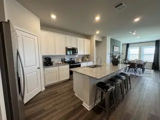 Model Home A modern kitchen with granite countertops, sleek appliances, and an open dining area with natural light streaming in.