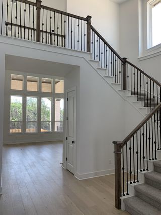 A grand entryway with a staircase and elegant iron railing, providing a bright, open view of the living area.