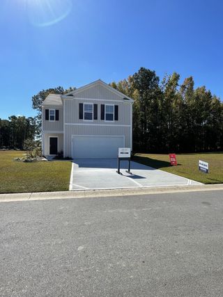 A modern two-story home with a spacious driveway and lush lawn in Evergreen by D.R. Horton (Holly Hill, SC).