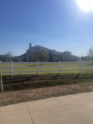 A modern estate with a white fence and expansive grounds in Tealpointe Lake Estates by Jamestown Estate Homes (Tomball, TX).