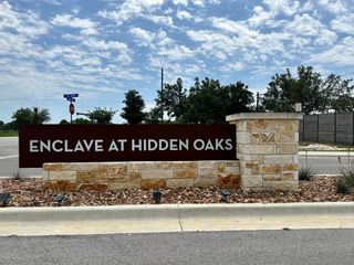 Community Amenities A welcoming entrance sign with stone accents at The Enclave at Hidden Oaks by Williams Homes (Georgetown, TX).