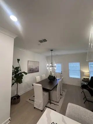 A cozy dining area featuring a dark wood table, soft lighting, and plush white chairs.