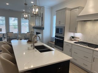 A sleek kitchen with quartz countertops, pendant lighting, and an open layout leading to a cozy living area with a fireplace.