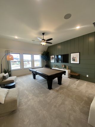 A stylish game room with deep green walls, a plush sectional, and built-in entertainment.