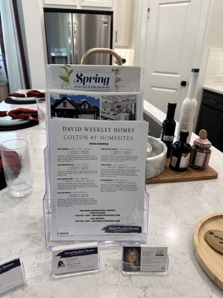 A modern kitchen with a marble countertop, stainless steel fridge, and organized brochures for Colton 45' Homesites.