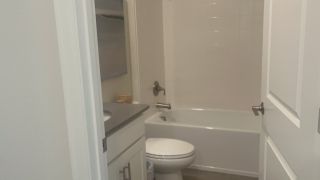 A cozy bathroom with a sleek vanity, modern fixtures, and a clean white bathtub.