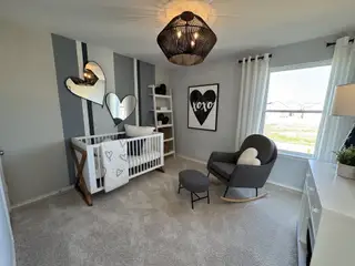 Model Home A cozy nursery with heart mirrors, a modern crib, and a comfy rocking chair under soft lighting.