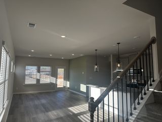 An inviting open-plan living area with large windows, modern kitchen island, and stylish pendant lighting.