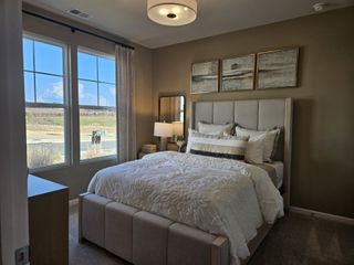Model Home A spacious master bedroom with a feature wall, large windows, and cozy neutral decor in Red Hawk Landing by HistoryMaker Homes (San Antonio, TX).