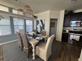Model Home A chic dining area with a woven chandelier, cozy seating, and elegant table setting, adjacent to a modern kitchen nook.
