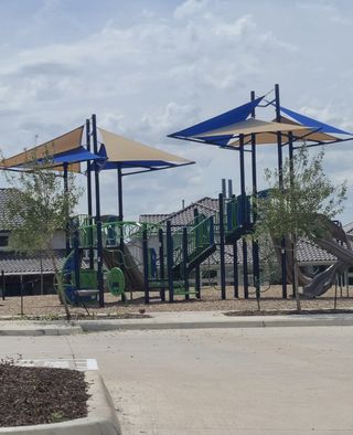 A vibrant playground with slides and shade structures in Duets 41s by Landon Homes (Frisco, TX).