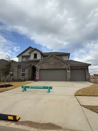 Street view A beautiful brick home with a spacious driveway in Lariat by Chesmar Homes (Liberty Hill, TX).