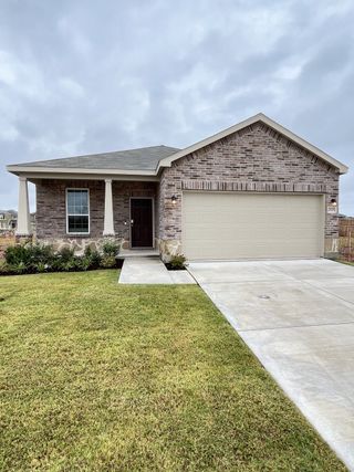 Street view A charming brick home with a manicured lawn and spacious driveway in Ashford Crossing by Centex (Princeton, TX).