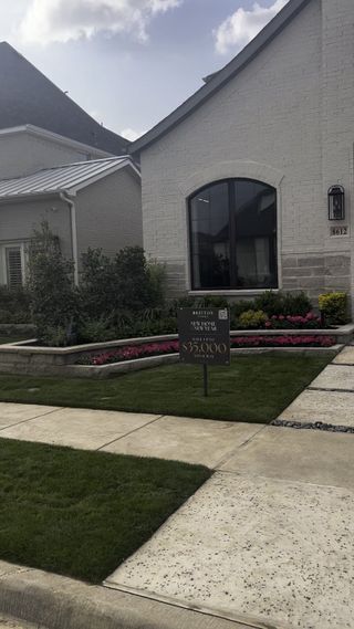 Street view A charming light brick home with lush landscaping in The Tribute 50' by Britton Homes (Frisco, TX).