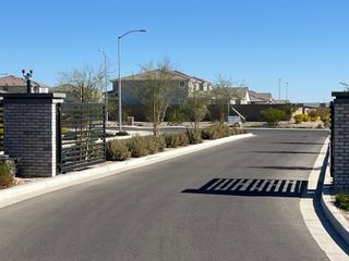 A gated entrance leads to modern homes in Zanjero Pass by D.R. Horton, Waddell, AZ, with manicured landscaping and clear skies.