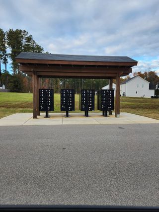 Community mailboxes under a sheltered wooden structure in Riverside by RiverWILD Homes (Zebulon, NC).