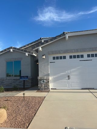 A modern home with a sleek facade and manicured yard in Avanti at Granite Vista by Elliott Homes (Waddell, AZ).