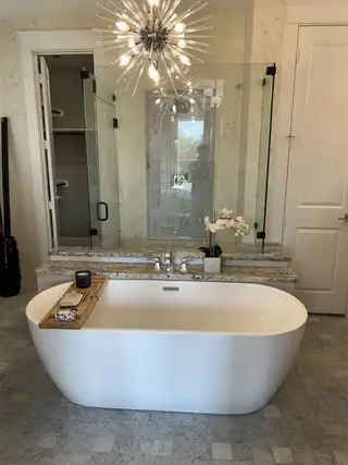 A luxurious bathroom featuring a free-standing tub, a sleek granite counter, and a striking modern light fixture.