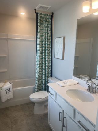A bright bathroom with a patterned shower curtain, sleek vanity, and modern fixtures creates a fresh and inviting space.