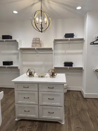 Model Home A spacious walk-in closet with elegant lighting, a central island, and ample shelving for storage.