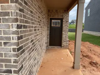 A charming brick entryway with a modern dark door in Towne Center by DRB Homes (Hampton, GA).
