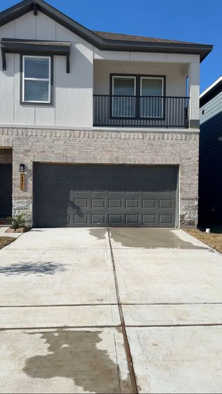 A modern two-story home with a balcony and spacious driveway in Eagle Landing by Saratoga Homes (Houston, TX).