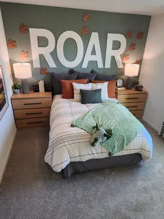 Model Home A playful dinosaur-themed bedroom with a bold accent wall and creative décor.